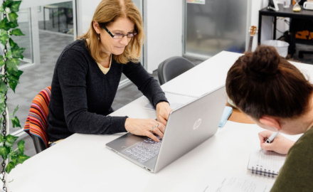 Educator Working In Childcare While Studying At Laptop