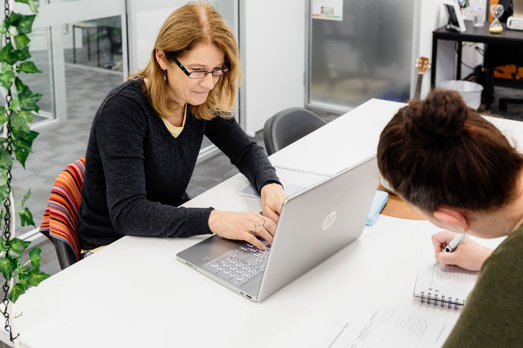 Educator Working In Childcare While Studying At Laptop